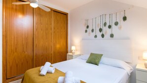 A hotel room with a bed, wooden wardrobe, and a ceiling fan. - Cosy Urban Penthouse In The Heart Of Fuengirola (FUENGIROLA)