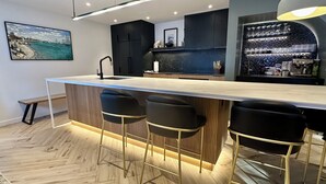 Una cocina moderna con una isla central, taburetes negros y una lámpara colgante.