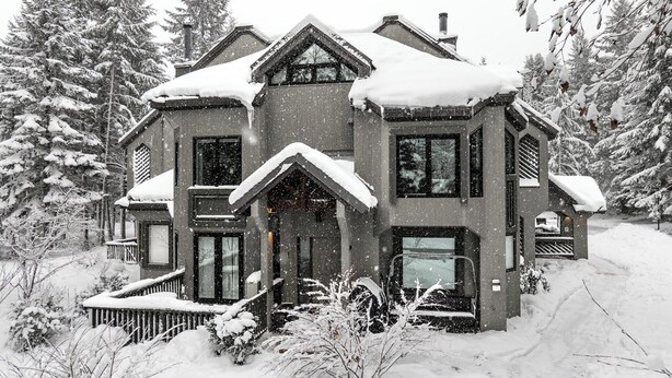 Una casa cubierta de nieve con techo simétrico y entrada central.