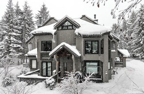 A snow-covered house with a symmetrical roof and a central entrance. - Whistler Village Ski-In/Ski-Out Skier’s Plaza, Luxury 4BR, Privacy & Proximity (Whistler)