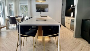Una cocina moderna con una isla central, sillas negras y una lámpara colgante.