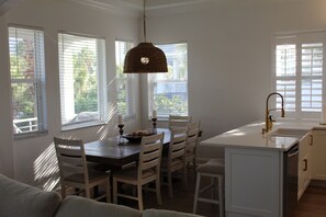 A dining area with a wooden table and chairs, a hanging light fixture, and a kitchen island with a sink. - Ocean Hammock Paradise-5BR 4BA, Private Pool, 1 Min walk to Beach,Family Retreat (Palm Coast)