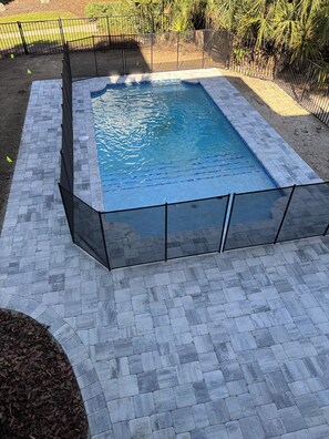 A rectangular swimming pool with a clear blue water surface, surrounded by a tiled deck and a metal fence. - Ocean Hammock Paradise-5BR 4BA, Private Pool, 1 Min walk to Beach,Family Retreat (Palm Coast)