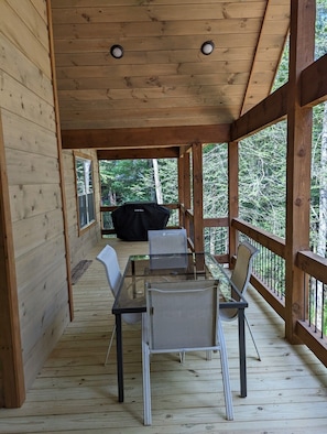 Enjoy dining and socializing in this cozy outdoor space with a grill and scenic forest views.
