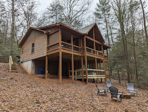 Eine zweistöckige Holzhütte mit einem Balkon, umgeben von einem Wald.