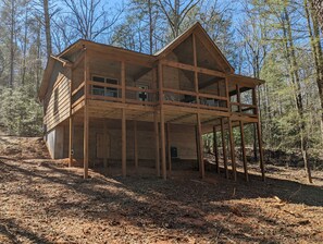 A large wooden cabin with multiple floors and balconies, surrounded by a forest.