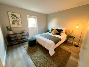 Quarto bem arrumado com cama, mesas de cabeceira, abajur e janela.