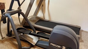 A PRECOR treadmill with a digital display, positioned against a white wall with a carpeted floor. - Are you traveling to Rochester? Be our guest!!  (Rochester)