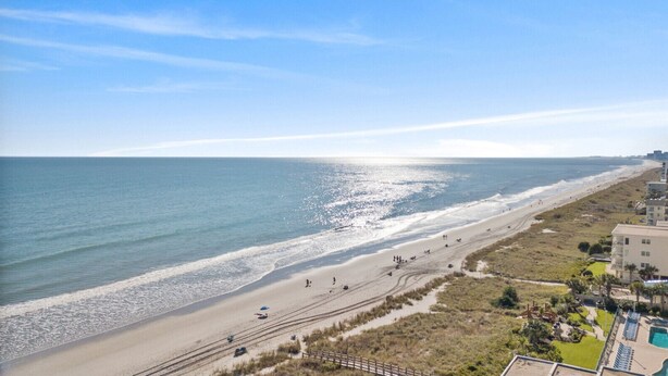 Une vue sur la plage avec un hôtel, une plage de sable et l’océan.