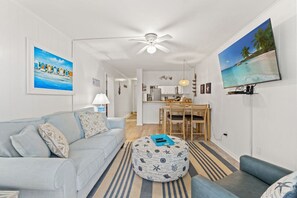 Un salon moderne avec un canapé, un pouf et un coin repas.