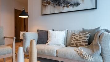 A modern living room with a grey sofa, a wooden coffee table, and a black pendant lamp.