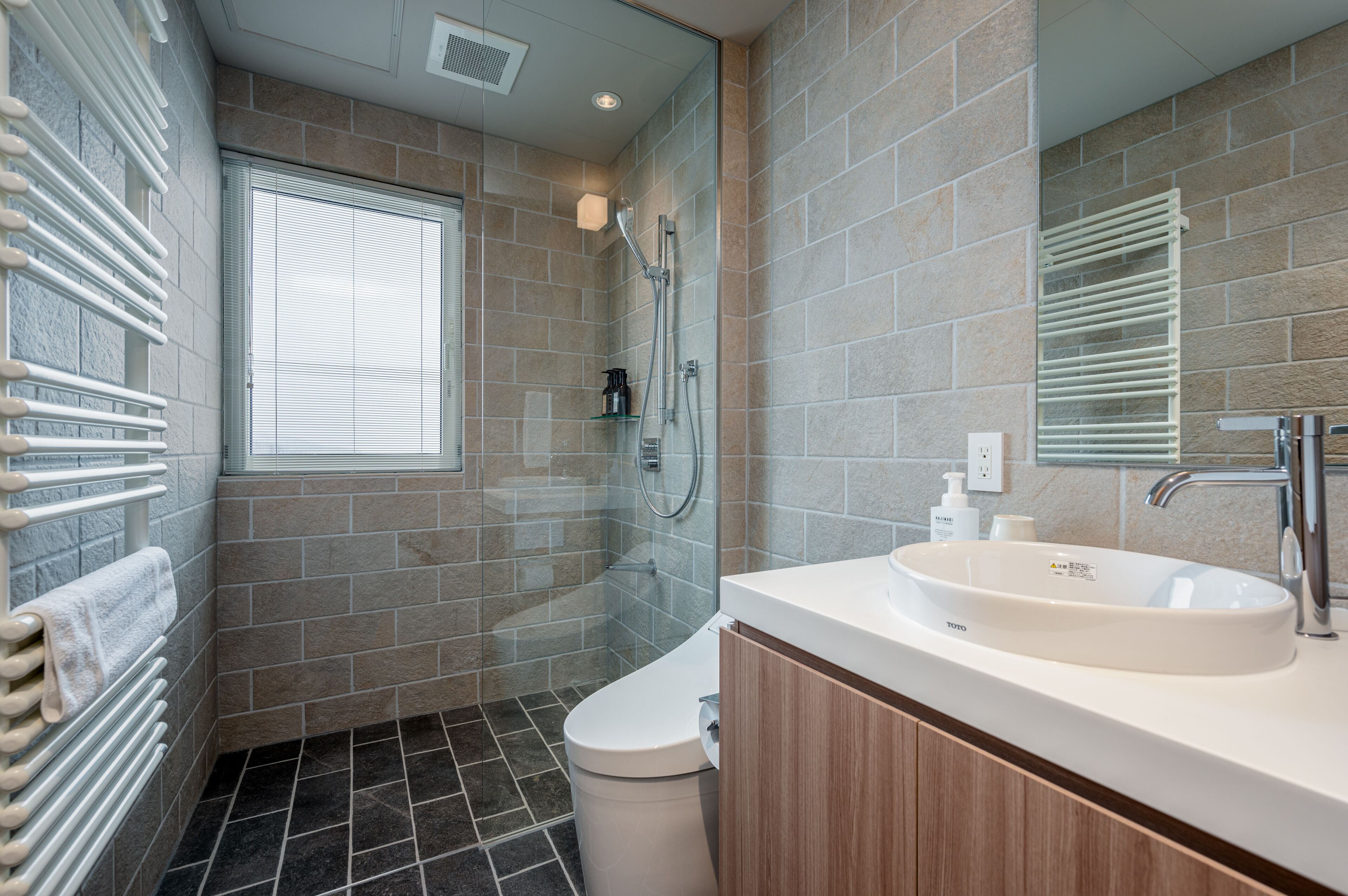 A modern bathroom with a glass-enclosed shower, a white sink, and a large mirror.
