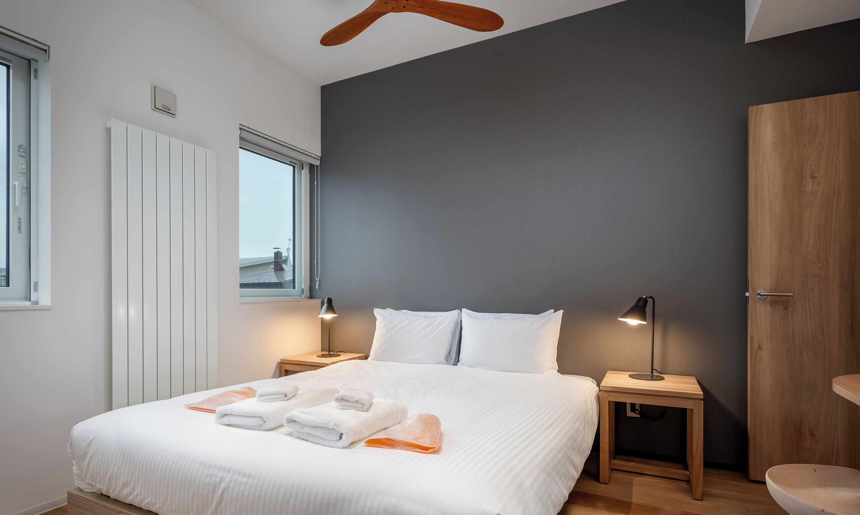 A modern bedroom with a large bed, bedside lamps, and a view through the window.
