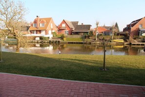 A residential area with houses, a pond, and a brick pathway.