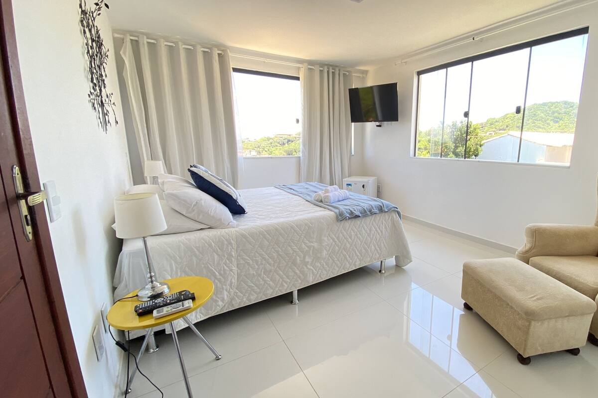Une chambre d’hôtel avec un lit, une chaise, une tél évision et une fenêtre donnant sur un paysage agréable.