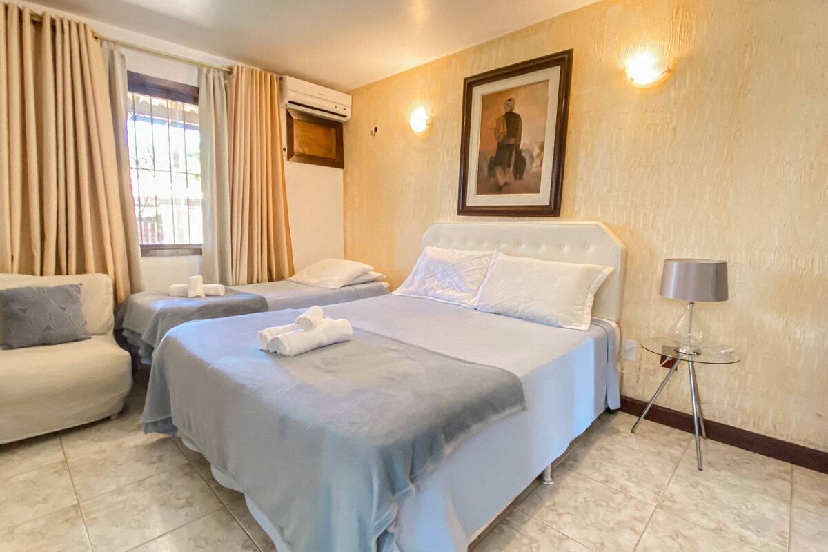 Une chambre d’hôtel avec deux lits, une chaise, une lampe et un tableau au mur.