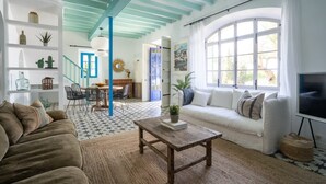 A living room with a sofa, coffee table, and a TV. There is a staircase leading to another room. - Ca'n Quinn (Deià)