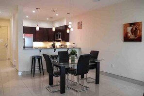A modern kitchen with dark cabinets, a central island, and pendant lighting. - Papaya Suite: 2 BR Condo on the Ocean (Myrtle Beach)