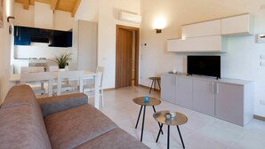 A modern living room with a sofa, two small tables, and a TV. - Beautiful apartment for 6 guests with WIFI, TV and patio (Ca' Savio)