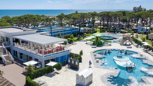 A resort with a pool area, outdoor seating, and a view of the sea. - Beautiful apartment for 6 guests with WIFI, TV and patio (Ca' Savio)