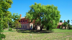 A building with a brick facade, a large tree in front, and a clear blue sky. - Cosy apartment for 8 people with WIFI, A/C, TV and patio (Ca' Savio)