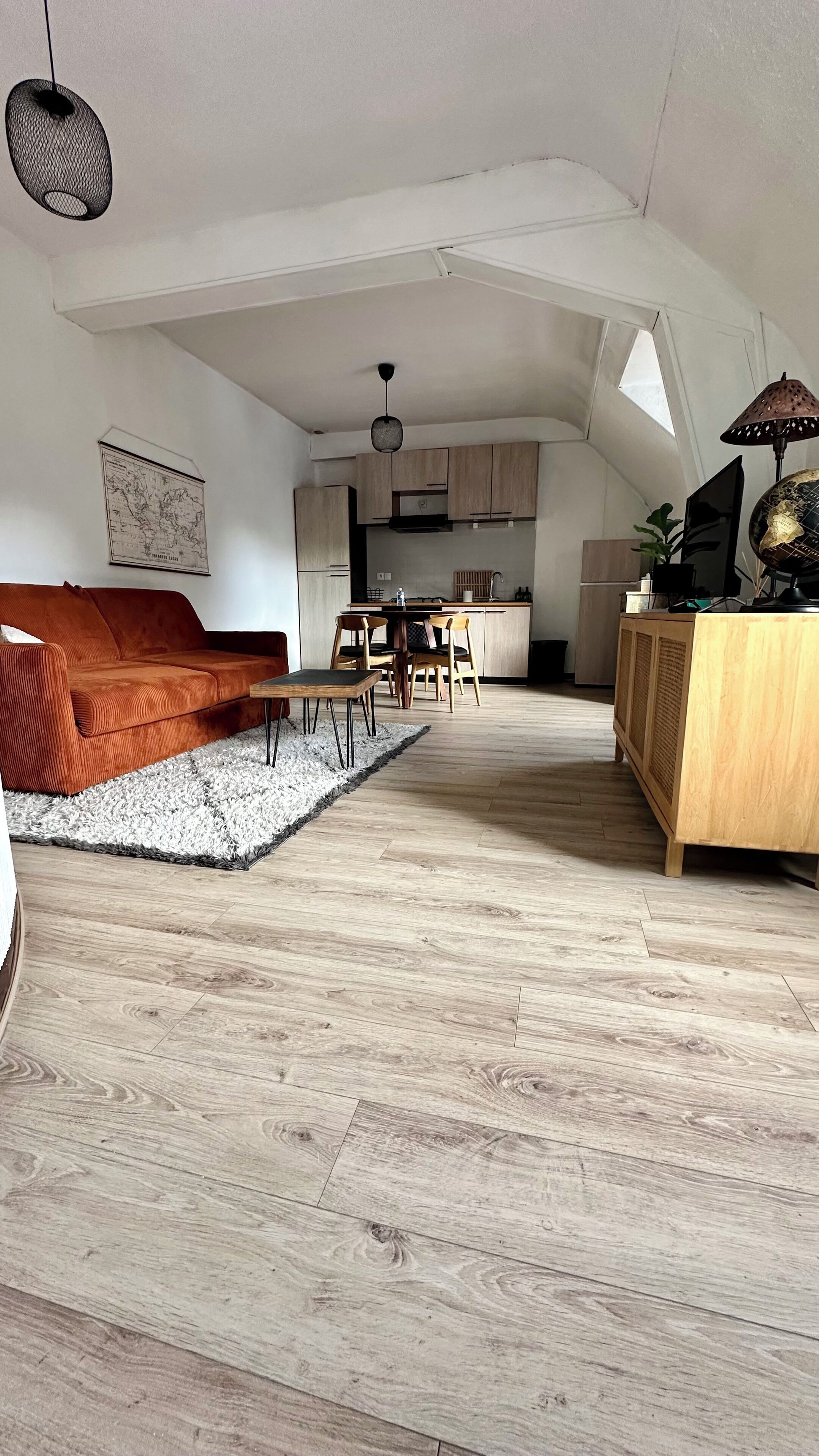 A spacious loft with a high ceiling, a cozy seating area with a sofa and chairs, a dining table, and a kitchen area.