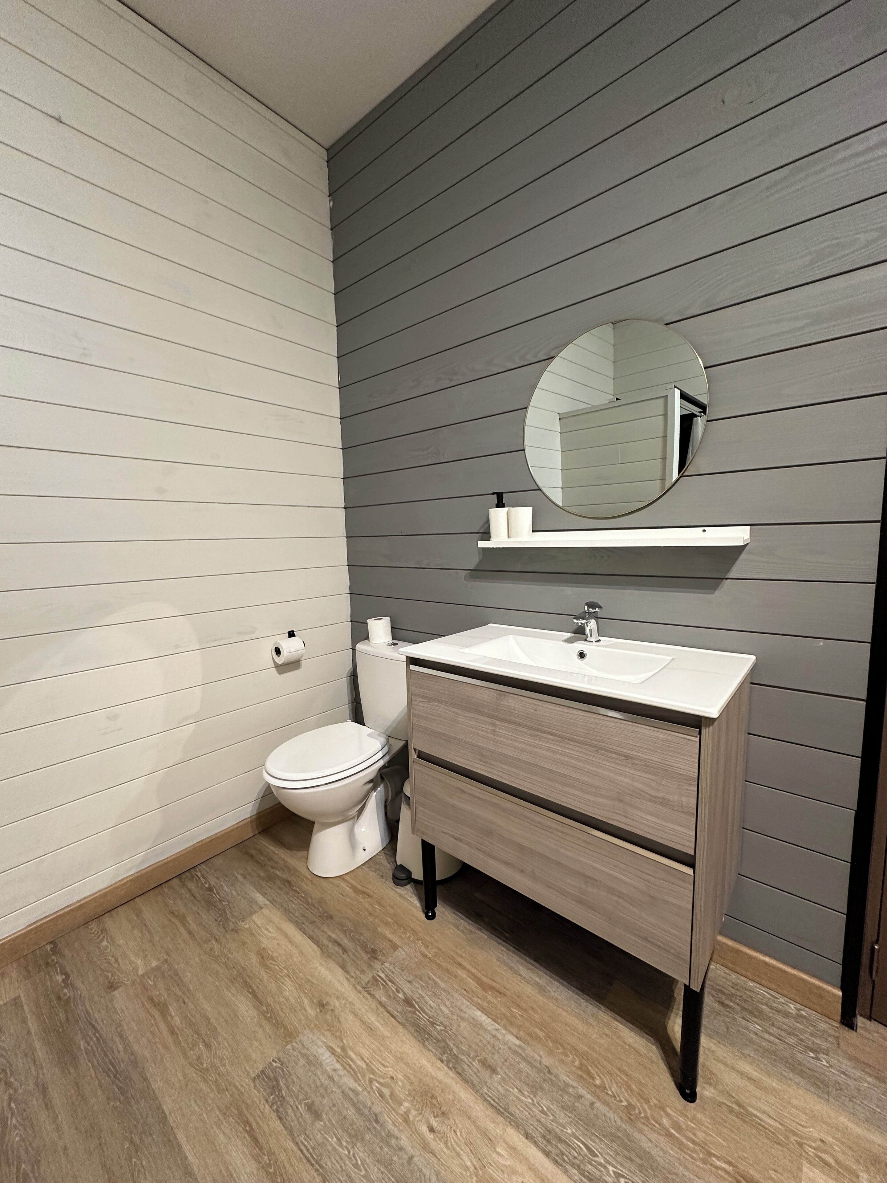A modern bathroom with a toilet, sink, and mirror.
