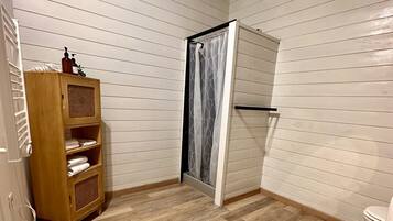 Une petite salle de bain avec un meuble en bois, un rideau de douche et des toilettes.