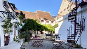 Une cour avec un chemin de gravier, des sièges extérieurs et un escalier.