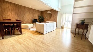 Un salon spacieux doté d’un plancher en bois, d’un canapé, d’une télévision et d’un coin repas avec une table et des chaises.