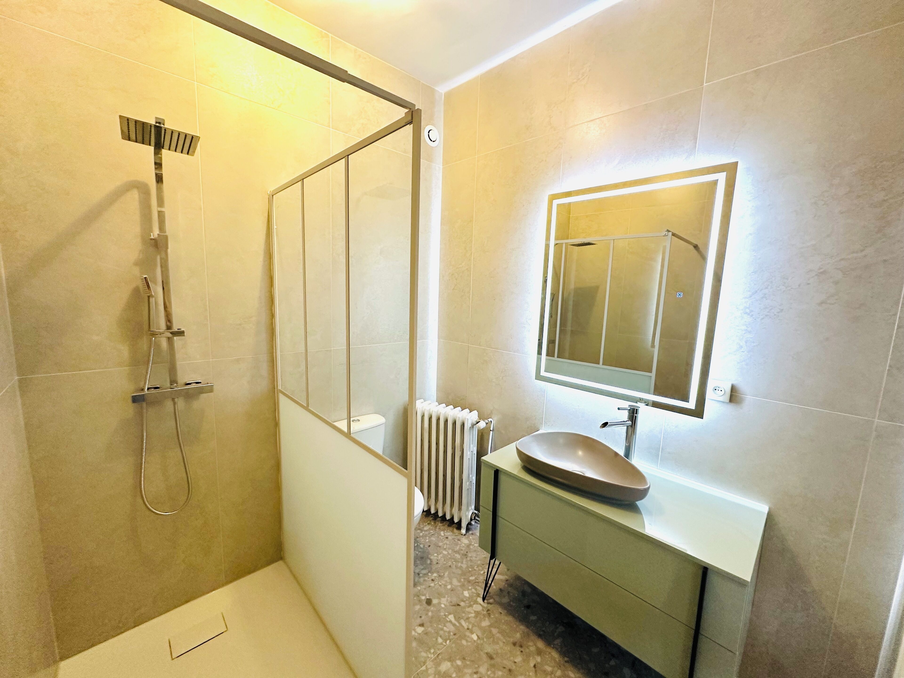 A modern bathroom with a glass shower enclosure, a white sink, and a mirror above it.