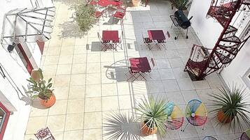 Pátio com área de estar externa, plantas em vasos e escada.