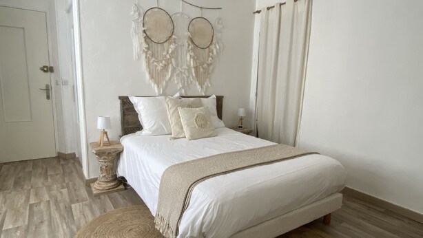 Une chambre à coucher avec un lit, des tables de chevet, une décoration murale et une fenêtre avec des rideaux.
