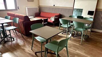 A room with a red sofa, green chairs, a wooden table, and a mirror.