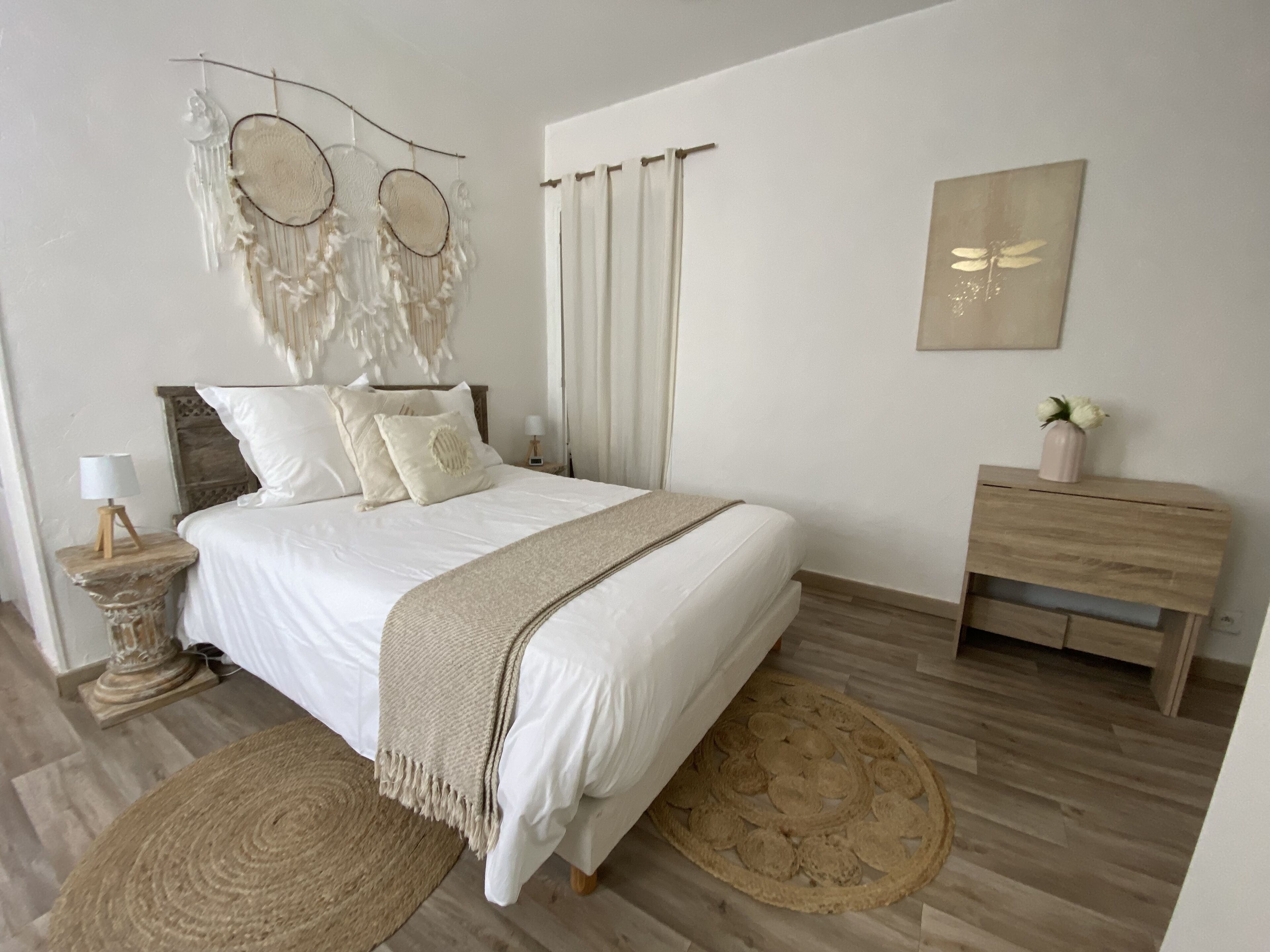 Un dormitorio con cama, mesitas de noche, cómoda y una obra de arte colgada en la pared.