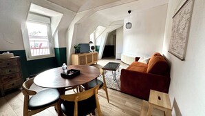 Une pièce confortable de style loft, comprenant une table à manger, des chaises, un canapé et un petit meuble en bois.