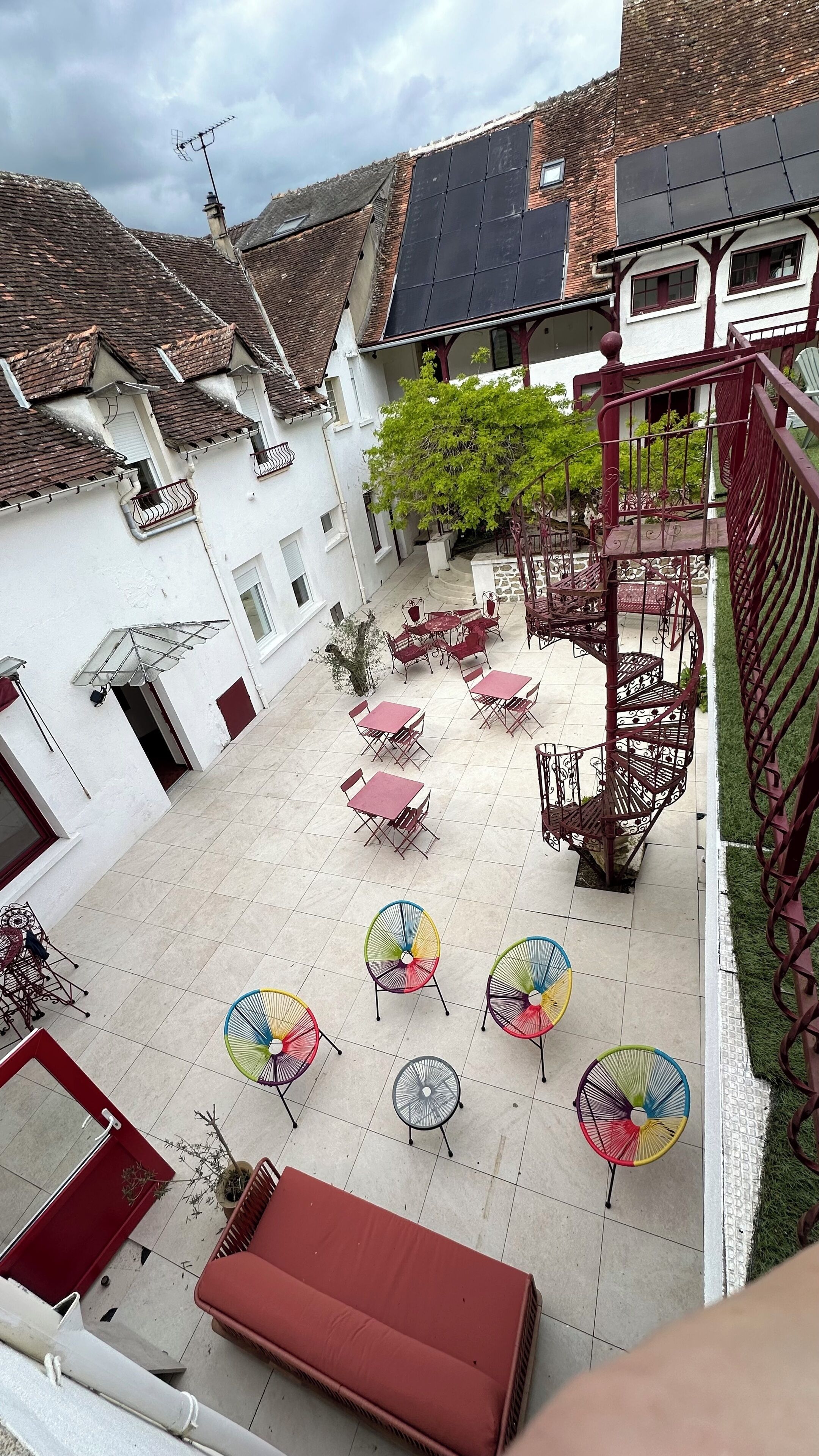 A courtyard with outdoor seating, a staircase, and a building with a tiled roof.