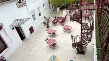 A courtyard with outdoor seating, a staircase, and a building with a tiled roof.