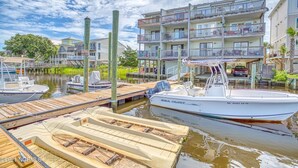 A marina with docked boats, a wooden dock, and a multi-story building with balconies. - 2 BR/2.5 BA beautiful, spacious waterfront Carolina Beach condo (Carolina Beach)