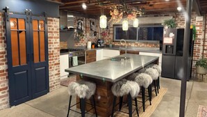 Una cucina moderna con una grande isola, sgabelli da bar, un frigorifero e un lavello.