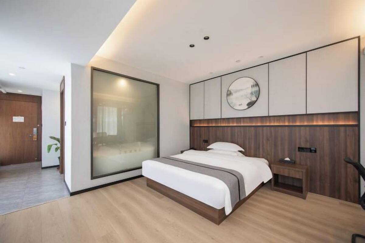 Un dormitorio moderno con una cama grande, una puerta corrediza de vidrio y un cabecero de madera.