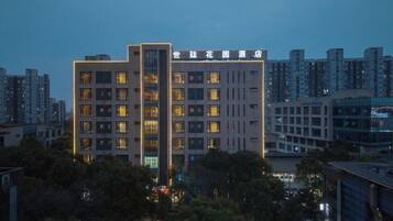 Un hotel de varios pisos con una llamativa franja de luces verticales en la fachada, rodeado de otros edificios.