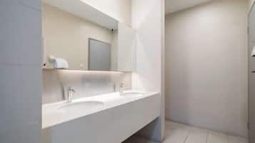 A modern bathroom with two sinks, a large mirror, and a shower area.