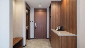 A hallway with a wooden door, a bench, and a countertop with a kettle. - City Garden Hotel (Suzhou Kunshan Huaqiao Lvdi Avenue) (Kunshan)