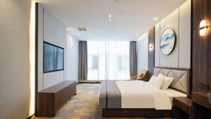 A modern hotel room with a large bed, a TV mounted on the wall, and a view of the city through large windows. - City Garden Hotel (Suzhou Kunshan Huaqiao Lvdi Avenue) (Kunshan)