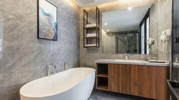 Een moderne badkamer met een vrijstaand bad, een houten wastafelmeubel en een grote spiegel.