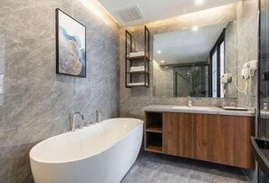 Un baño moderno con una bañera independiente, un tocador de madera y un espejo grande.