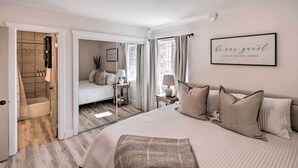 Een slaapkamer met een groot bed, een nachtkastje met een lamp, een spiegel en een lijst aan de muur.
