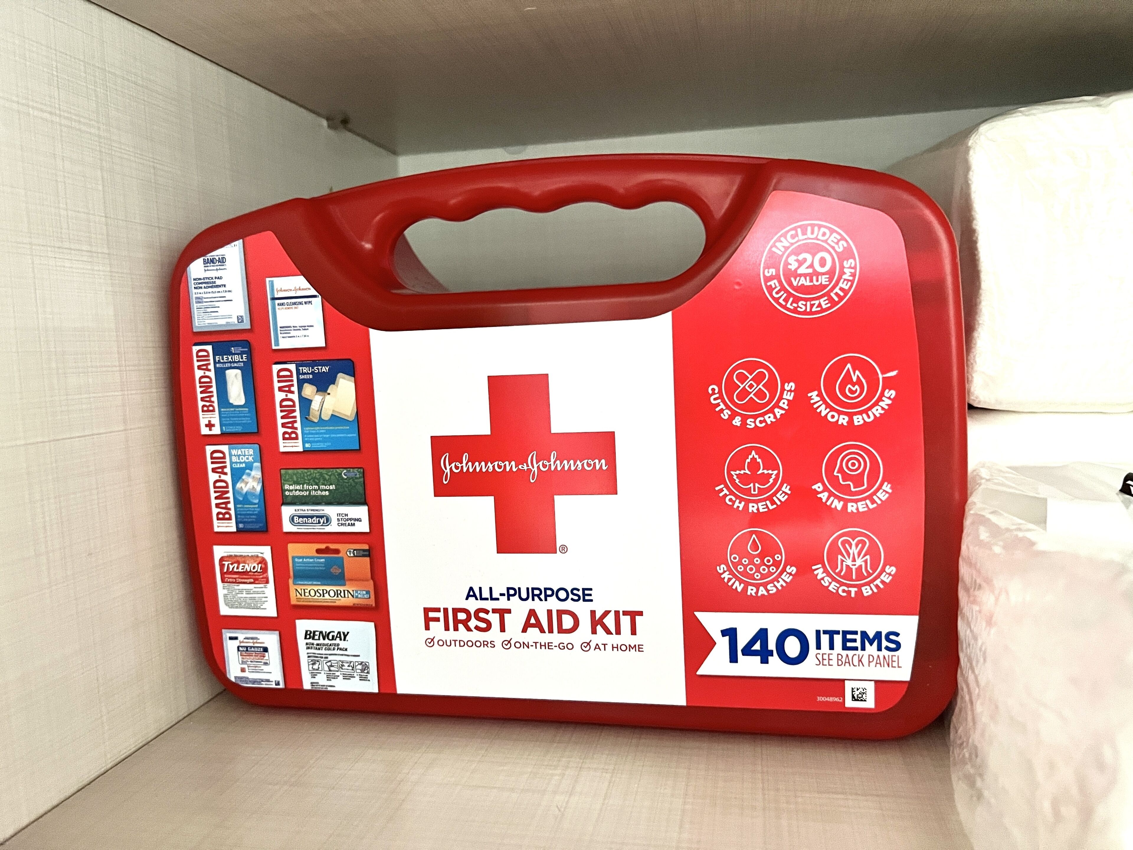Une trousse de premiers secours rouge, dotée d’une poignée et contenant 140 articles, ainsi qu’un symbole en forme de croix blanche.