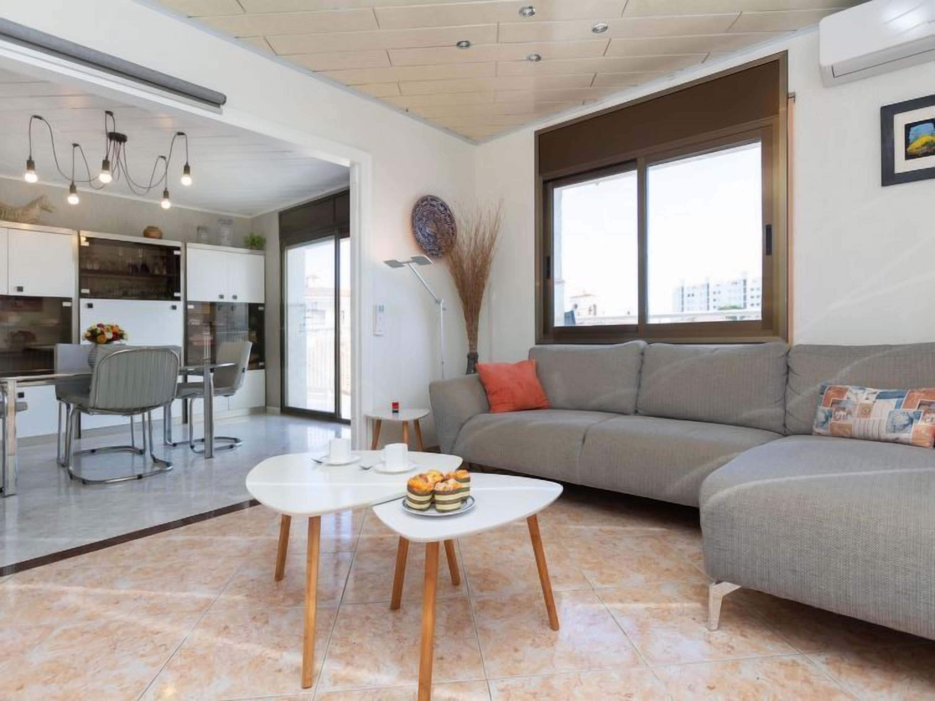 Een moderne woonkamer met een bank, een salontafel en een eethoek met stoelen en een tafel.